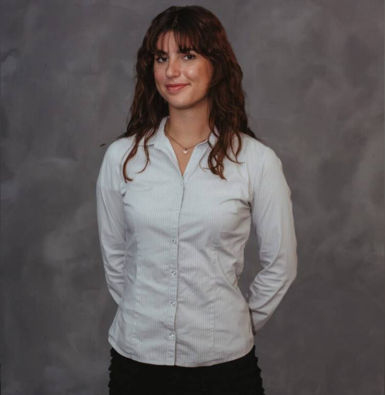 A woman standing in front of a gray wall.